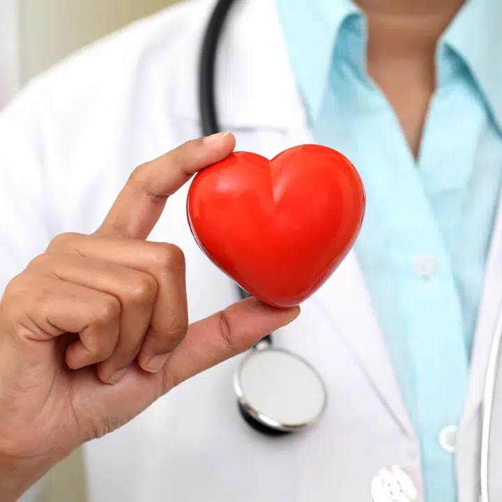 A health practitioner in a white coat holding a red heart