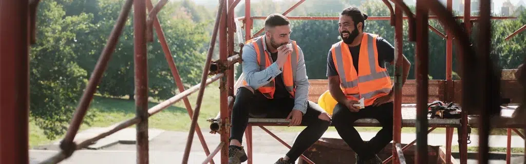 Two men on a construction site talking and eating lunch, following workplace suicide first aid training