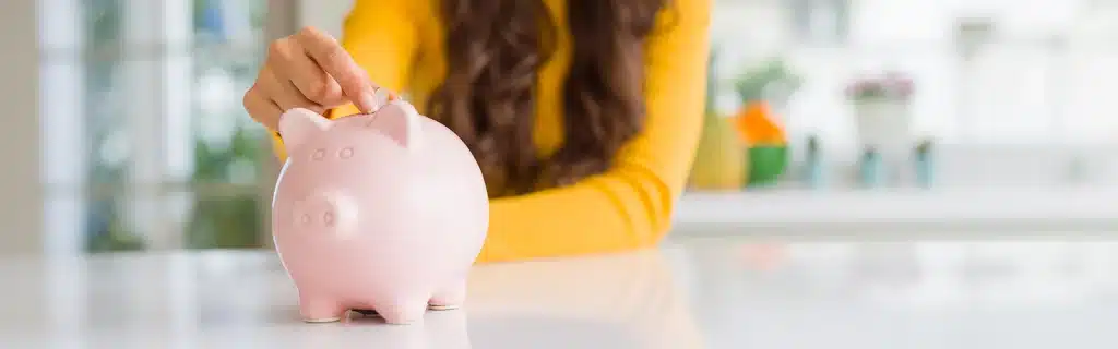 A woman putting a coin into a piggy bank, representing the idea of a workplace wellbeing budget