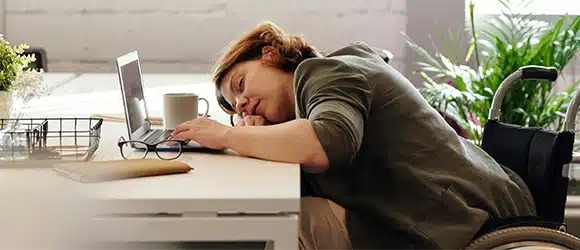 A woman asleep at her desk at work, illustrating why sleep is important