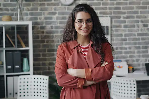 A woman with folded arms smiling and looking at the camera