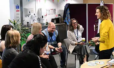 A group of employees listening to a health practitioner talk during a wellbeing roadshow.