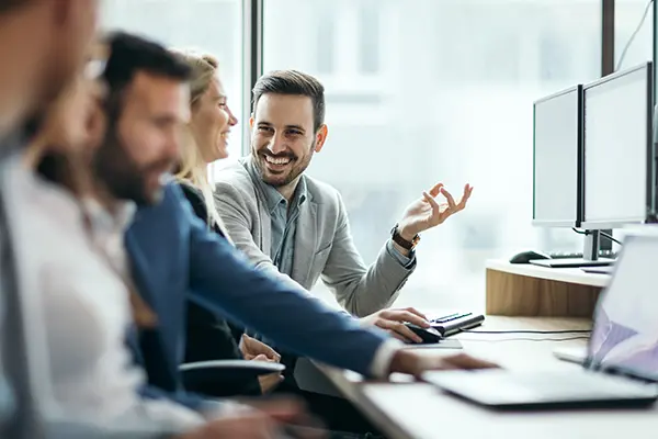 A man and woman sitting at a desk talking and smiling
