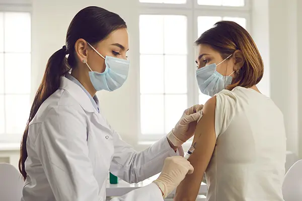A woman receiving a flu vaccine from a nurse during a workplace flu clinic
