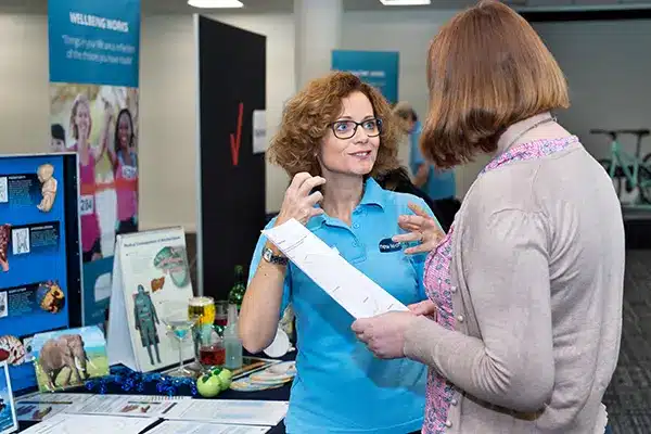 A New Leaf Health practitioner chatting to an attendee at a Corporate Health Fair