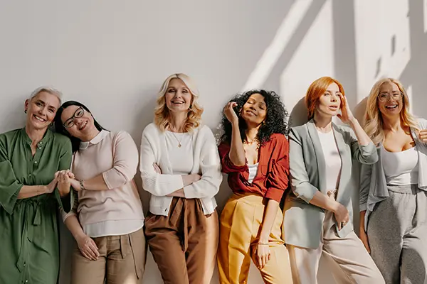 A group of women of various ages (including menopause age) standing shoulder to shoulder and smiling at the camera