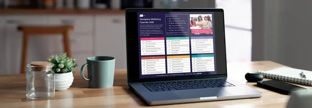 A laptop on a table showing the 2026 Workplace Wellbeing Calendar from New Leaf Health