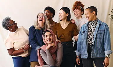 A group of diverse women laughing and smiling, posing for the camera