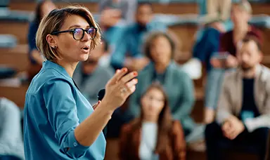 A woman standing in front of a crowd delivering a presentation
