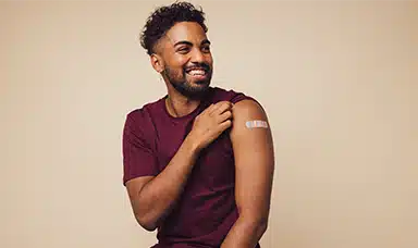 A man smiling with a plaster on his arm having participated in a workplace flu clinic