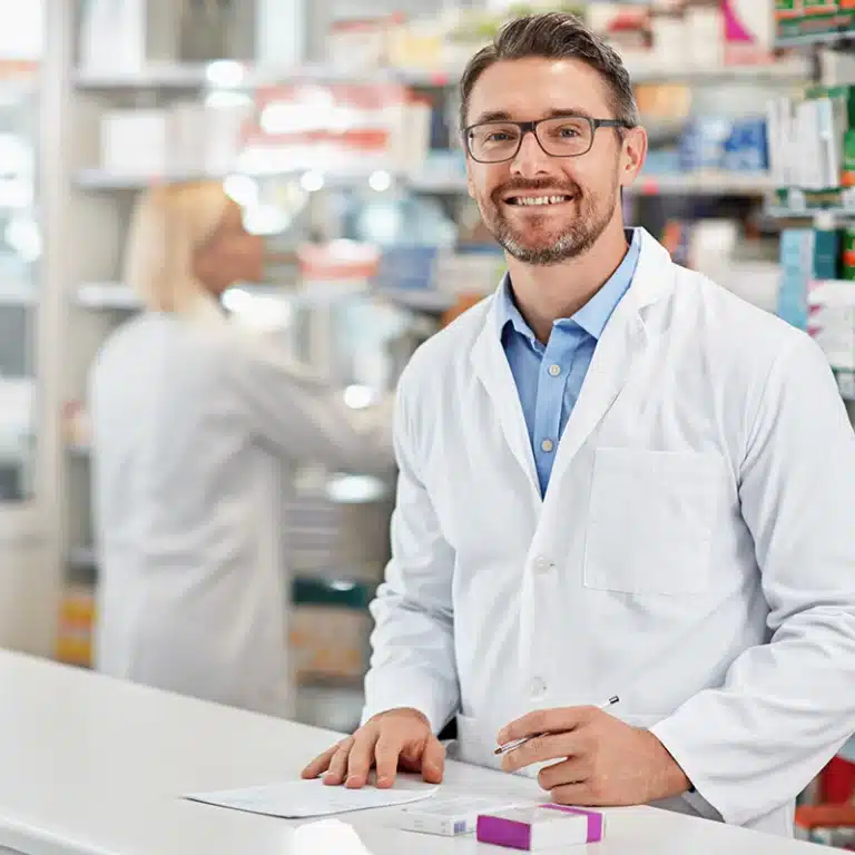 A smiling male pharmacist standing at a counter