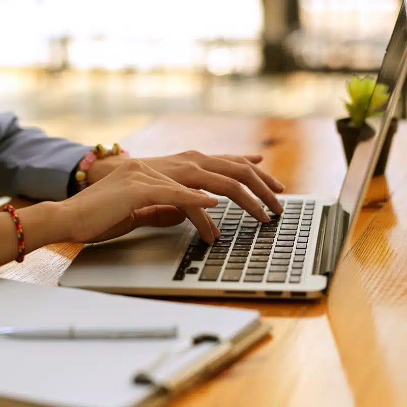 A woman's hands typing on a laptop