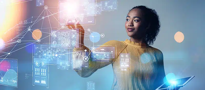 A woman manipulating digital data floating in front of her whilst holding a tablet