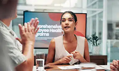 A woman delivering a presentation on employee health and workplace wellbeing to colleague