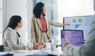 A woman presenting charts and stats from a wellbeing strategy to colleagues