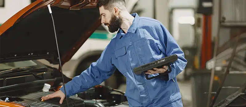 A mechanic performing an MOT on a car, in contrast to a workplace health MOT