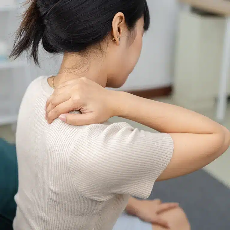 A woman holding her sore neck needing a workplace massage service