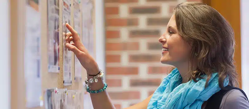 A woman reading a poster for a wellbeing event, boosting engagement and helping reduce the workplace wellbeing programme cost