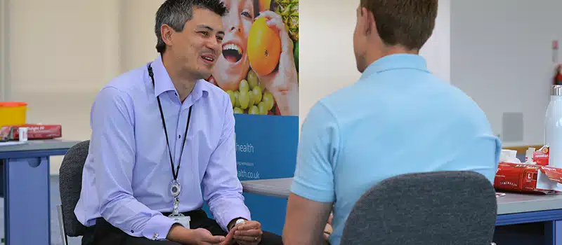 A New Leaf Health practitioner performing a workplace health screening on a smiling employee