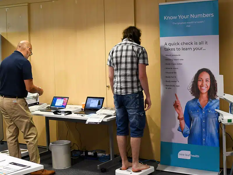 An employee taking part in a health screening using body composition scales