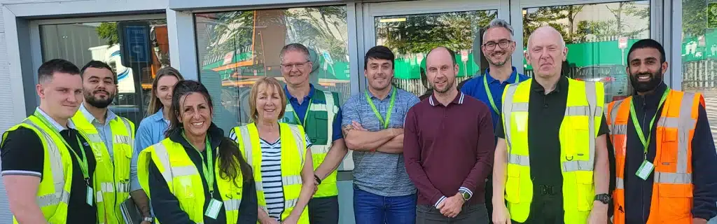 How many Mental Health First Aiders does your workplace need - a group of mental health first aiders posing for a photo wearing hi-vis vest and MHFA lanyards