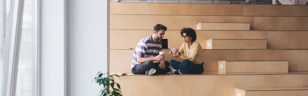 Two colleagues sitting together and talking in a relaxing workspace, showcasing how to prevent burnout at work