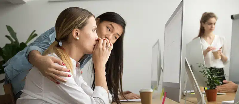 A manager comforts an employee sitting at a desk, showcasing how to prevent burnout at work