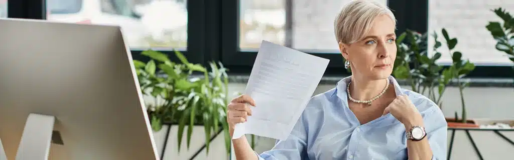 A woman sat at a desk in an office experiencing side effects from menopause and mental health at work