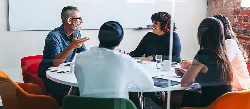 A group of employees meeting at a desk showcasing the prevalence of neurodiversity at work