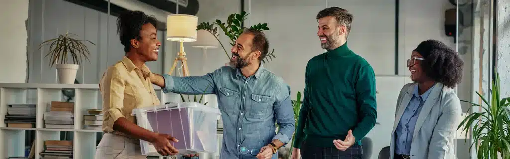 A group of office employees welcome a coworker back as she returns to the office