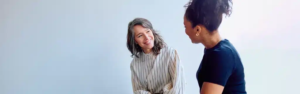 Two menopause-age women talking and smiling