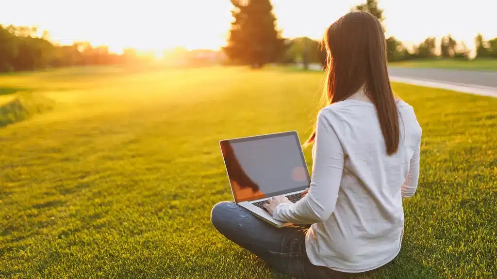 A women with seasonal affective disorder remote working in a green field in the sunshine